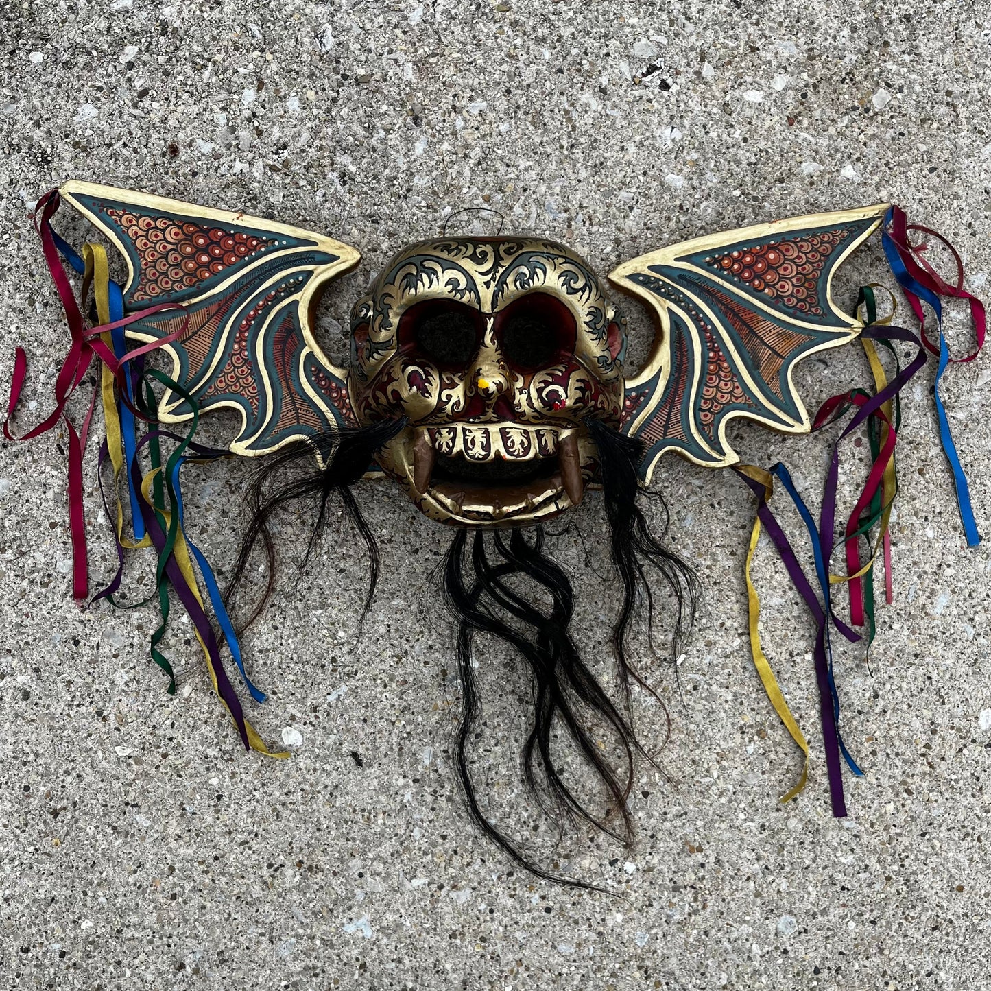 Hand carved flying demon skull with ribbons.