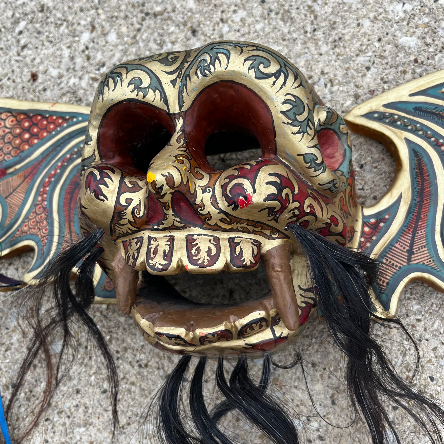 Hand carved flying demon skull with ribbons.