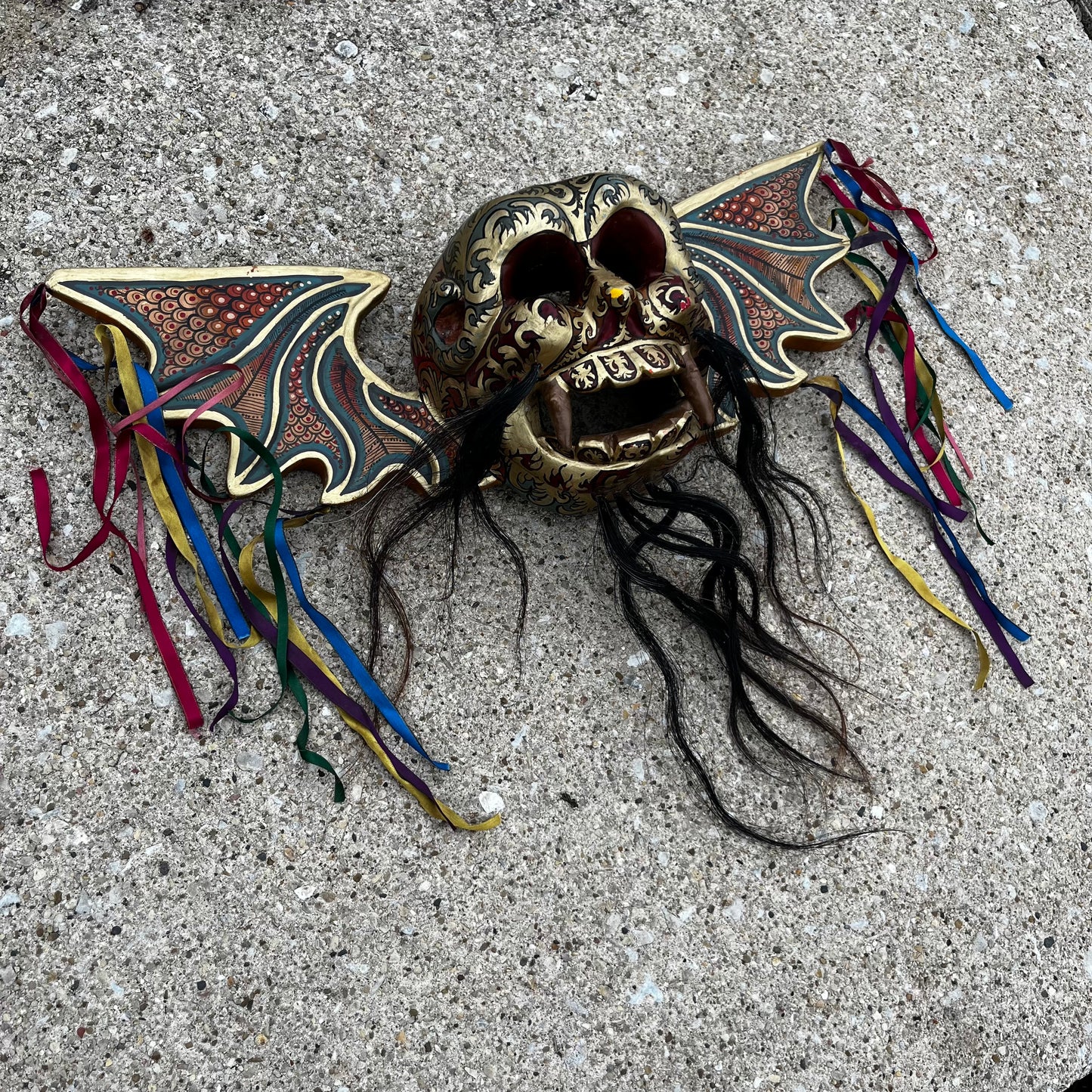 Hand carved flying demon skull with ribbons.