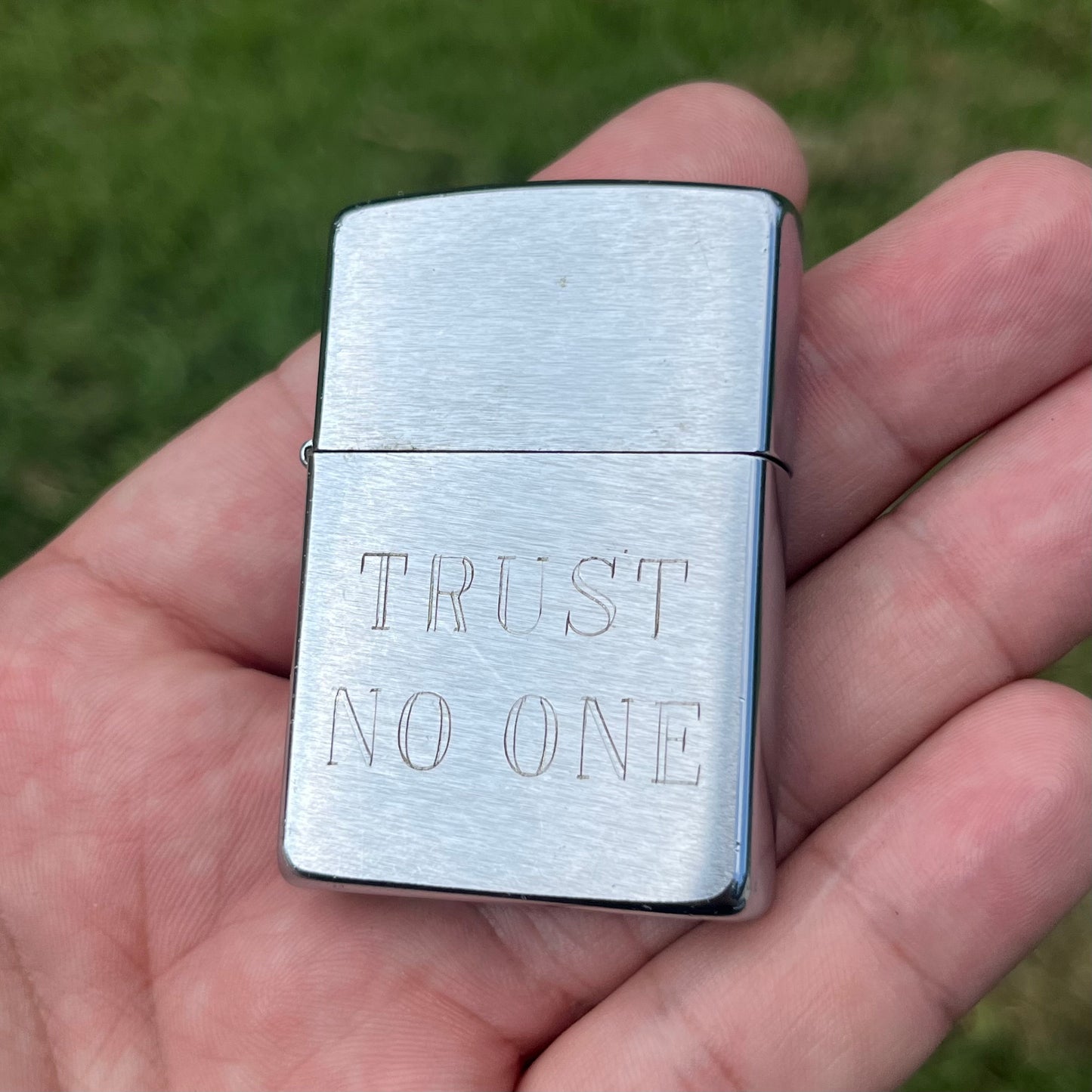 Y2K “Trust No One” Zippo flip lighter.