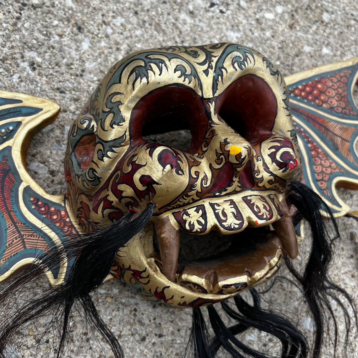 Hand carved flying demon skull with ribbons.